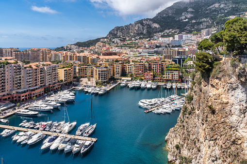 April 30, 2023: This photo shows the glamorous and luxurious principality of Monaco, nestled on the stunning French Riviera. The image captures a panoramic view of the cityscape, featuring the towering hillside, opulent architecture, and the Mediterranean Sea. The photo is also adorned with the yachts moored in the harbor.