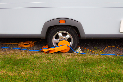 Close up shot of caravan wheel with yellow wheel clamp on it, protecting the caravan against being stolen whilst on Caravan Park.