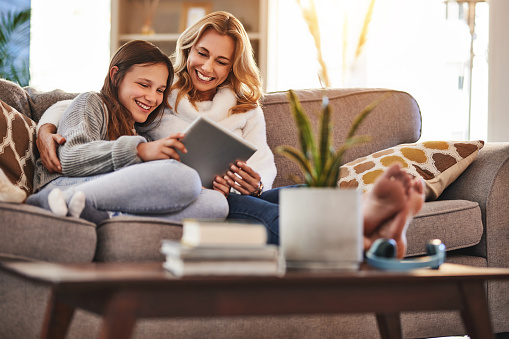 Love, mother and girl with a tablet, couch and happiness at home, bonding and connection for social media. Family, mama and daughter with technology, watching movies and online reading in living room