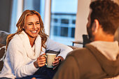 Couple relax, happy woman with coffee and man have funny conversation, spending quality time at home. Love, care and trust with people laughing together with communication, latte drink and happiness