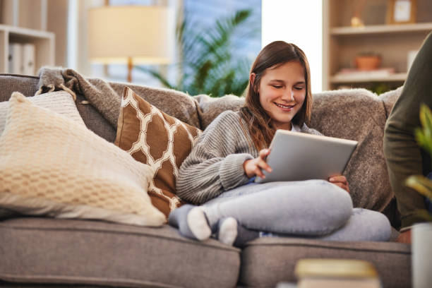 istock Technology, young girl using her tablet while on sofa in living room and comfortable in home. Smile, communication or networking and happy or relaxed woman with mobile device on social media on couch 1486635913