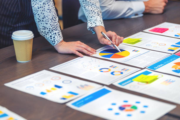 istock Paperwork and hands on a board room table at a business presentation or seminar. 1486640869