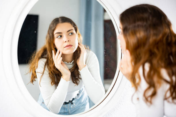 istock Woman standing in front of mirror and looking at her face 1486643500