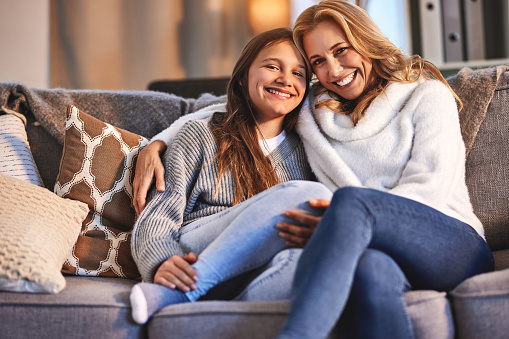 Couch, smile and portrait of mom and teenager girl in living room, love and time to relax in evening at home. Lounge, happy face of mother and daughter on sofa together, bonding and happiness in hug.