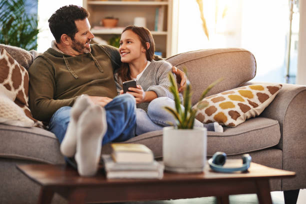 Phone, happy man and teenager girl on sofa checking social media meme and quality time to relax in home. Lounge, dad and daughter on couch, internet post and laughing together, bonding and happiness. stock photo