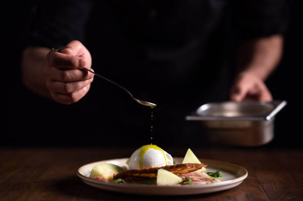 A male chef pouring sauce on a plate of carpaccio with burrata cheese A male chef pouring sauce on a plate of carpaccio with burrata cheese. carpaccio parmesan cheese beef raw stock pictures, royalty-free photos & images
