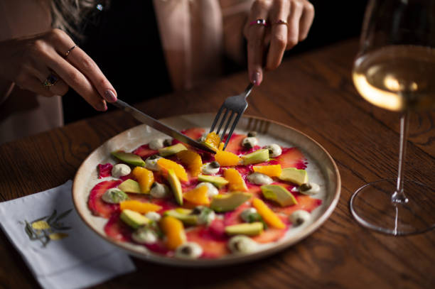 vista ravvicinata di una mano di donna che mangia carpaccio di manzo - beef carpaccio foto e immagini stock