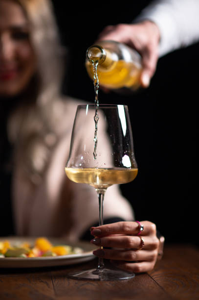 cameriere che serve vino bianco a una bella donna - wine bottle food wine restaurant foto e immagini stock
