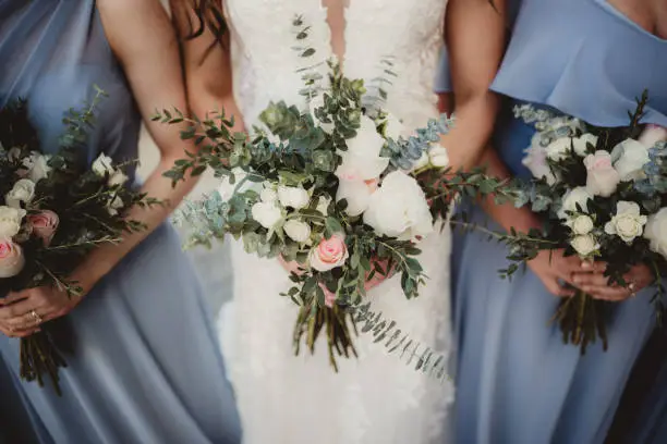 Bride and bridesmaids in blue dresses with bunches of white roses