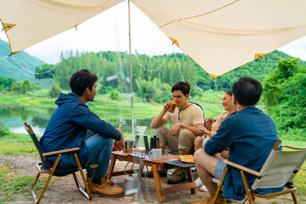 istock Group of Asian people having breakfast drinking coffee while camping together at nature park. 1486659471