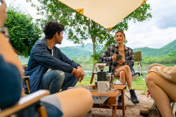 istock Group of Asian people having breakfast drinking coffee while camping together at nature park. 1486659563