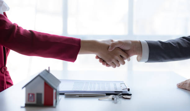 Real estate agent shaking hands with a client to sign a home purchase contract and congratulate the client. stock photo