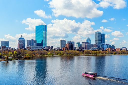 Boston, Massachusetts, USA - April 25, 2023:  A pink Duck Boat Tour vehicle sailing on the Charles River with Boston's Back Bay skyline in the background. Boston Duck Tours is a privately owned company that operates historical tours of the city of Boston using renovated World War II amphibious DUKW (aka Duck) vehicles.