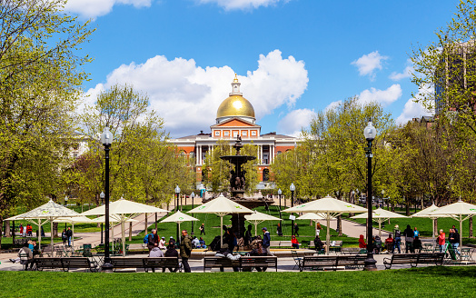 Boston, Massachusetts, USA - April 25, 2023: Massachusetts State House, the state capitol and seat of government for the Commonwealth of Massachusetts, as viewed across the public park Boston Common. The Brewer plaza and fountain are in the foreground.