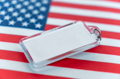 a shiny keychain with a white label for text on the background of the US flag. Copy space.