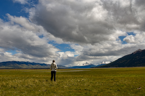 Female tourist enjoying the wide patagonian landscape with andes mountains and lake Lago Roca, which is part of Lago Argentino, near El Calafate, Argentina