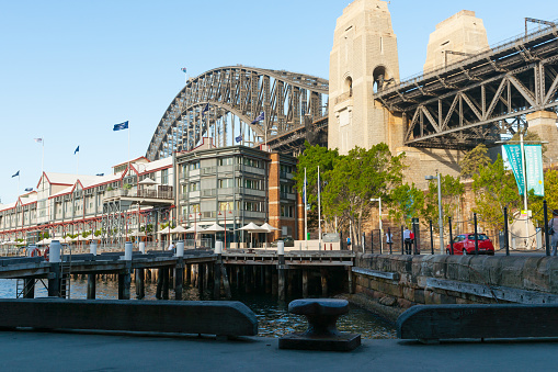 Sydney Australia - January 26 2011; Sydney Harbour Bridge and stone piers with waterside buildings and wharf.