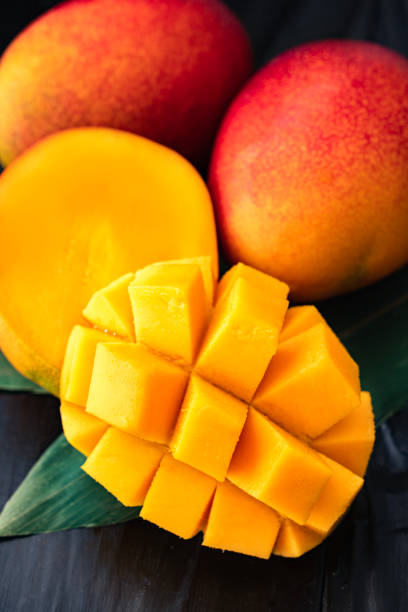 спелое и сочное вкусное манго на черном деревянном столе - seed food ingredient fruit стоковые фото и изображения