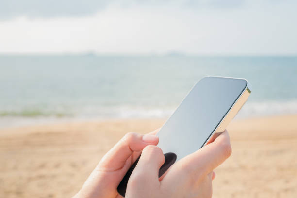 istock Hand using smartphone on the beach, Summer vacation concept. 1486699934