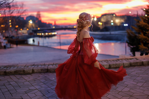 Beautiful mature woman dancing on city quay with beautiful sunset and city lights in background