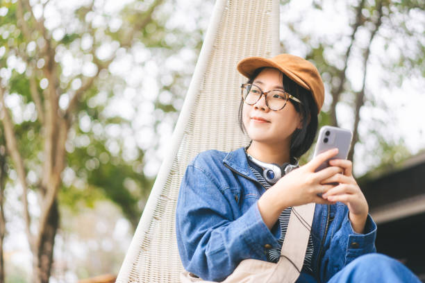 asian woman relax sitting use smartphone and headphone for mental therapy with at outdoor lifestyle - fashion women denim farm imagens e fotografias de stock