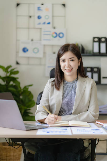 istock Pretty asian businesswoman using laptop and calculator finance graph document for doing financial mathematics on table, report, accounting, statistics and analytical research concept in office 1486703280