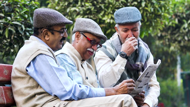 Older male friends reading newspaper at park