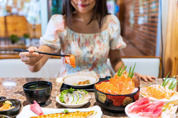 giovane donna asiatica che mangia sashimi impostato nel ristorante giapponese - buffet thai cuisine asian ethnicity food foto e immagini stock