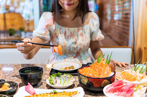Young Asian woman eating sashimi set in japanese restaurant