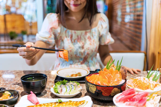 młoda azjatka jedząca zestaw sashimi w japońskiej restauracji - thai culture food ingredient set zdjęcia i obrazy z banku zdjęć