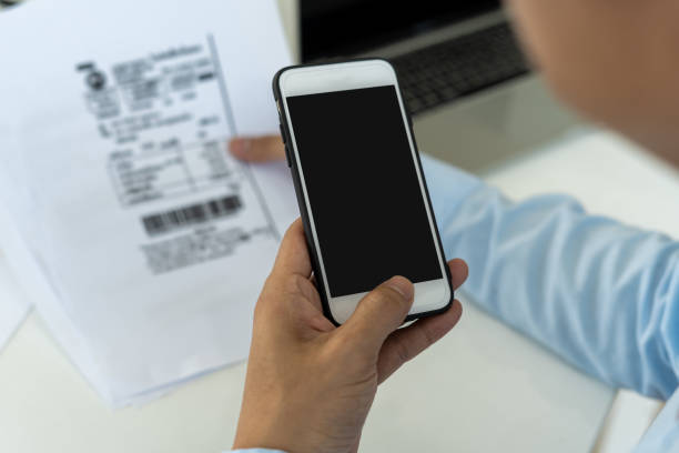 istock hand holding smart phone to scan QR code from invoice on papers for the bills. Scan, bar code online bill payment concept 1486716757