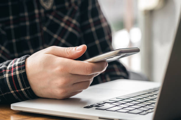 istock A man holds a smartphone and works on a laptop. 1486723691