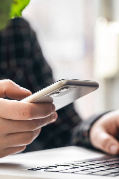 istock A man holds a smartphone and works on a laptop. 1486723707
