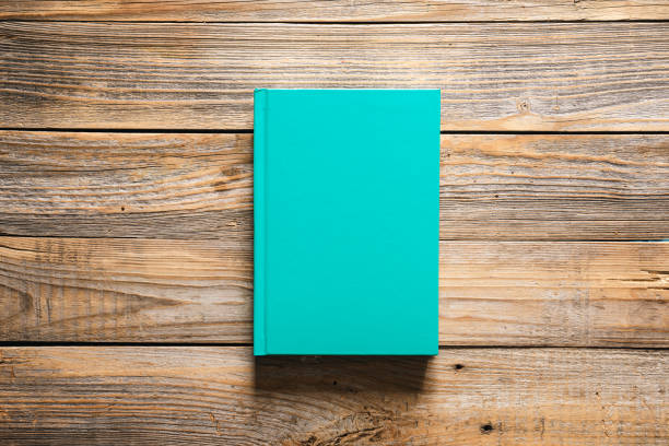 istock Closed green book on wooden background, top view. 1486725972