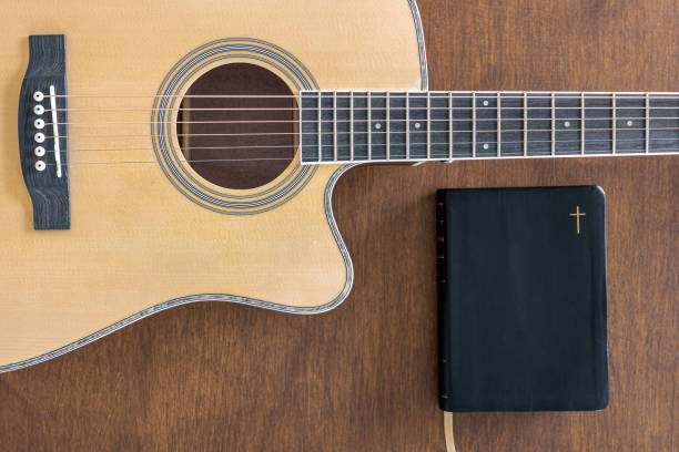 istock Guitar and bible book on wooden background, top view. 1486729832