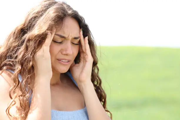 Woman suffering head ache in a field