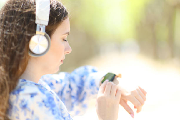 Woman listening audio with headphone using smartwatch Woman listening audio with headphone using smartwatch YouTube to MP3  stock pictures, royalty-free photos & images