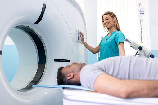 Doctora que observa a un paciente sometido a una tomografía computarizada. Médico en uniforme usando una máquina de tomografía con paciente acostado en el hospital photo