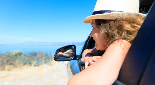 istock Happy young woman driver with straw hat looking from car window outside 1486740113