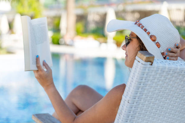 Free Stock Photo of A woman sitting on a deck by a pool reading a book ...