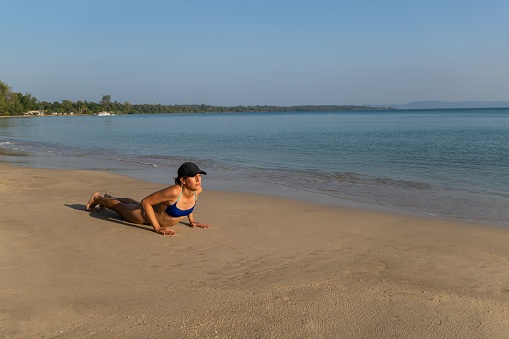 A Caucasian woman enjoying a relaxing yoga session on the beach in Thailand.