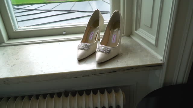 Close-up of a pair of fancy high heels by the window. Wedding shoes.