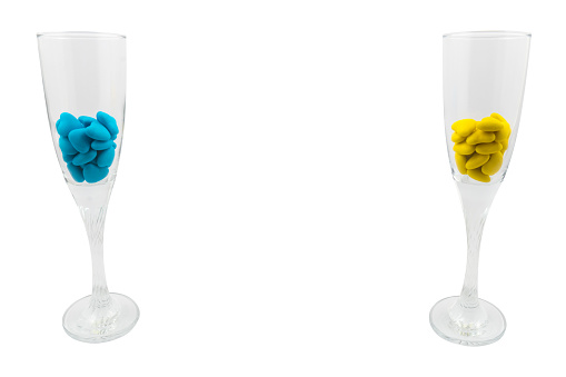 Two glasses with yellow and blue heart-shaped candies (close-up) isolated on a white background. State symbols of Ukraine. View from above
