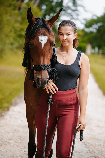 Portrait of a beautiful young woman posing with her brown Arabian horse in the nature. Color editing. Part of a series.