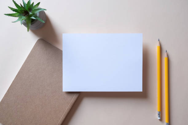 istock Workspace with note book, blank greeting card, pencil and cactus on beige background. 1486745925