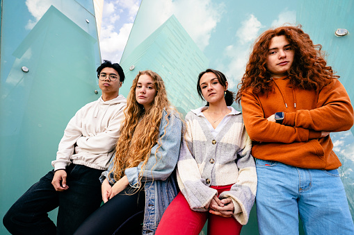 Portrait group of young Gen Z friends standing with serious expression in the city