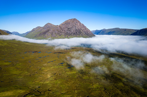 Aerial view of mountain peaks rising above low lying fog in a deserted valley (Glencoe, Highlands, Scotland)
