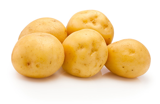 Raw potatoes varied shapes and colors after harvest on brown paper isolated on white background