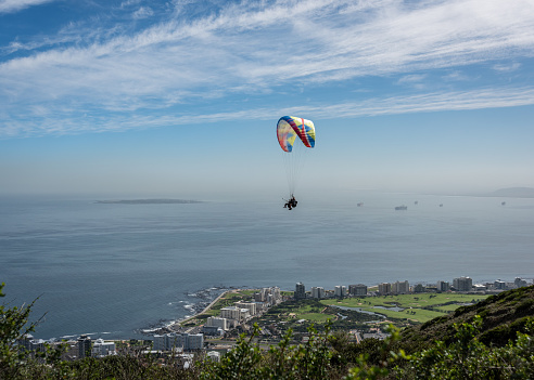 Paraglided flying over the city with an ocean backdrop