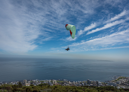 Paraglider flying over the city with an ocean backdrop